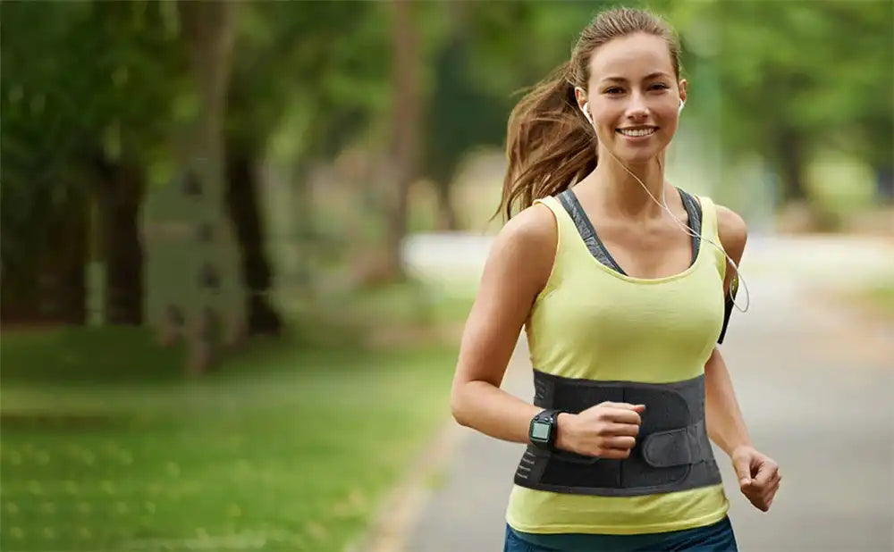 A happy and active woman jogs confidently in a park while wearing the PRP back support belt. The brace provides essential lumbar support, helping her prevent injury and enjoy her workout with a smile.