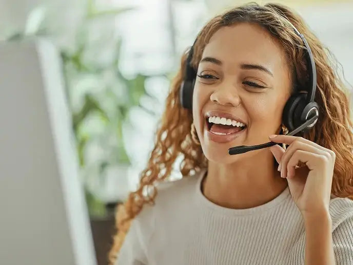 A cheerful female PRP customer service representative with curly hair is laughing warmly while speaking into her headset. Her joyful expression conveys enthusiasm, dedication, and a friendly attitude, ensuring customers receive a positive and professional support experience.